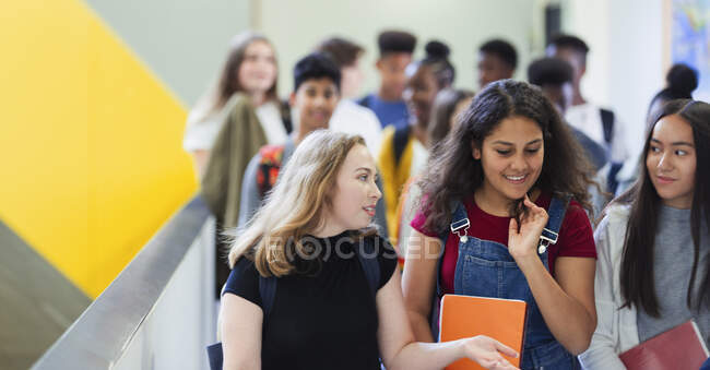 Junior lycéennes marcher et parler dans le couloir — Photo de stock