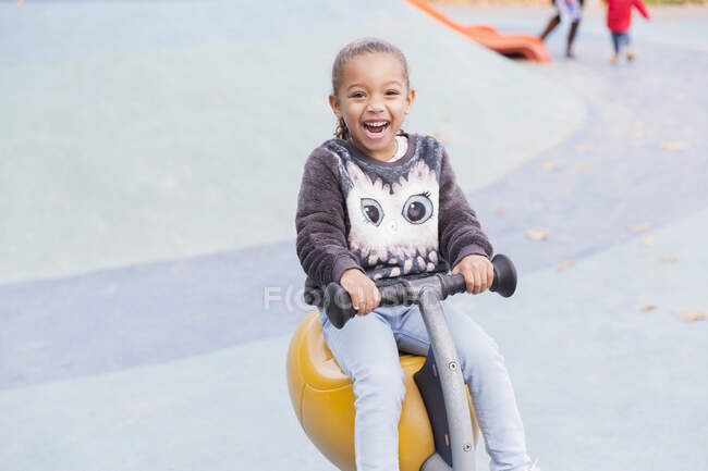Retrato sonriente, chica entusiasta jugando en el patio de recreo - foto de stock