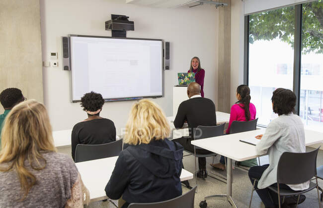 Інструктор жіночого коледжу провідний урок на проекційному екрані в класі — стокове фото
