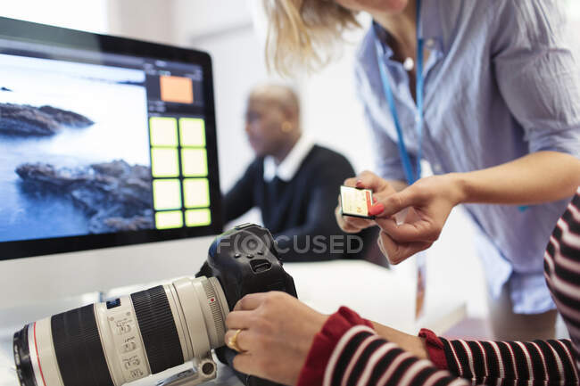 Photography students with digital camera and memory card at computer — Stock Photo
