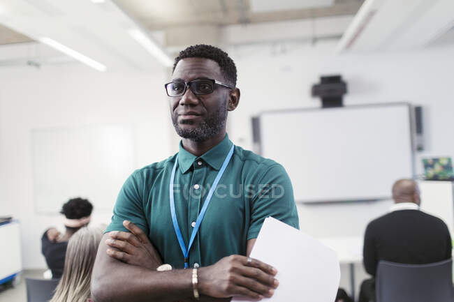 Портрет уверенный мужчина-инструктор со скрещенными руками в классе — стоковое фото
