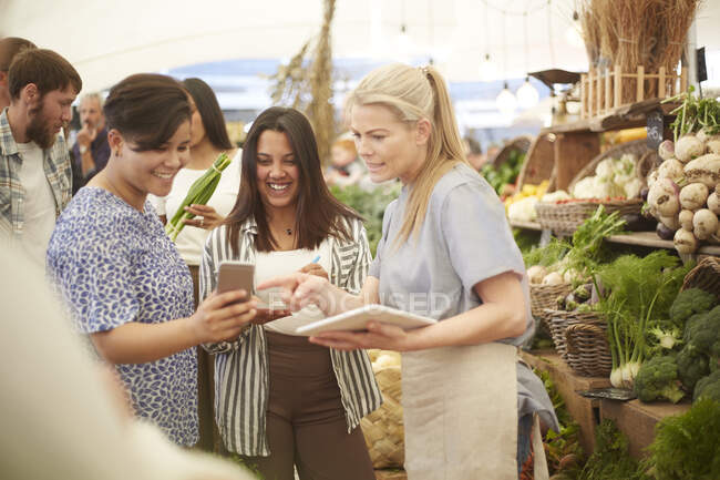 Women with digital tablet and smart phone working at farmers market — Stock Photo