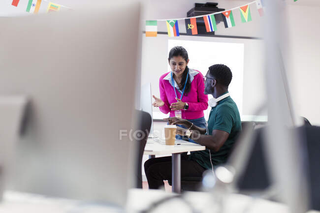 Community college instructor talking with student at computer in computer lab classroom — Stock Photo