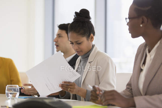 Mujer de negocios revisando el papeleo en la reunión de la sala de conferencias - foto de stock
