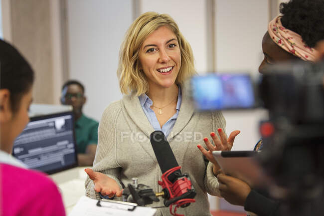 Estudiantes de periodismo comunitario sonrientes y confiados filmando en el aula - foto de stock