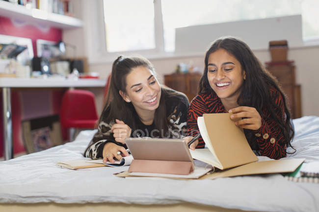 Adolescente menina amigos estudando fazendo lição de casa na cama — Fotografia de Stock