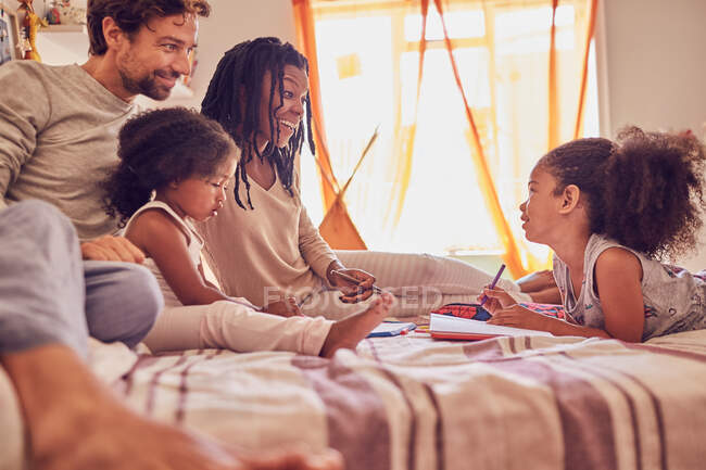 Young family coloring on bed — Stock Photo