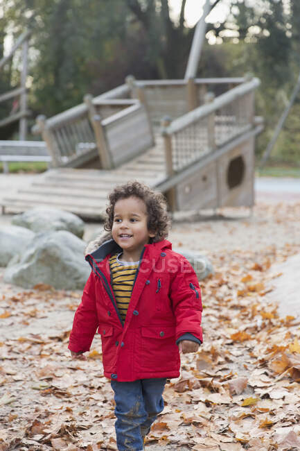 Bambino sorridente che cammina nel parco autunnale — Foto stock