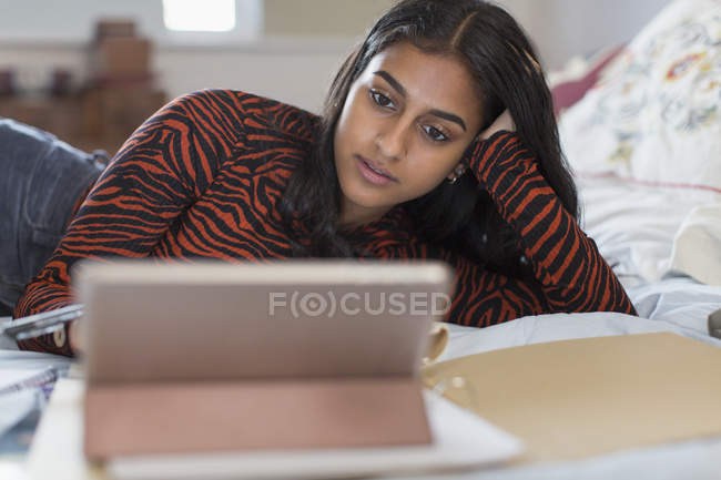 Konzentriertes Teenager-Mädchen lernt am digitalen Tablet auf dem Bett — Stockfoto