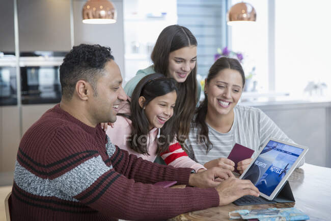 Happy family planning vacation at digital tablet in kitchen — Stock Photo