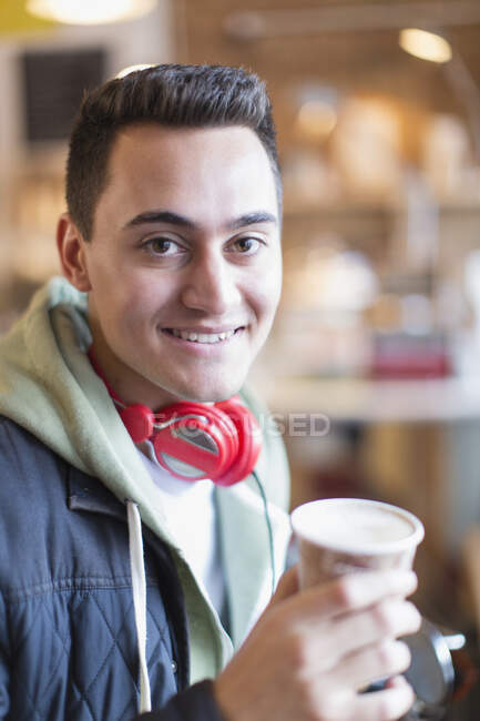 Retrato sonriente, joven confiado bebiendo café en la cafetería - foto de stock
