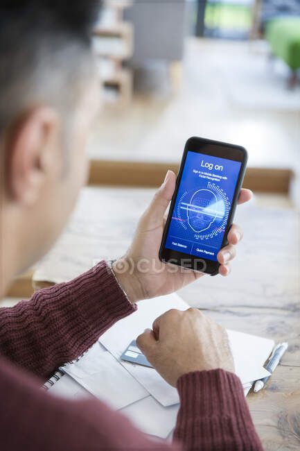 Mann loggt sich mit Gesichtserkennung auf Smartphone ein und bezahlt Rechnungen online — Stockfoto