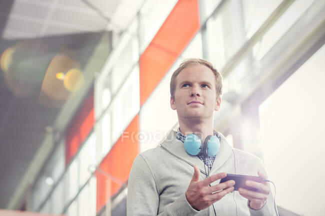 Umsichtiger junger Mann mit Kopfhörer und mp3-Player — Stockfoto