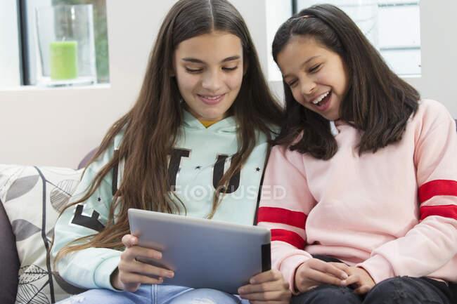 Smiling sisters using digital tablet — Stock Photo