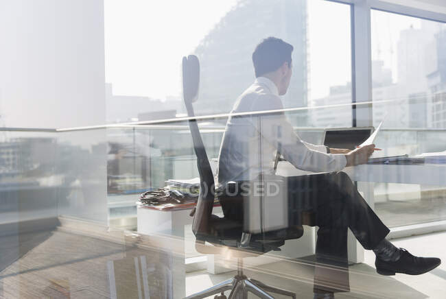 Businessman working in sunny, urban office — Stock Photo