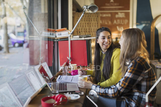 Smiling female college students studying at cafe window — Stock Photo