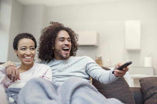 Coppia felice rilassante, guardando la TV sul divano del soggiorno — Foto stock