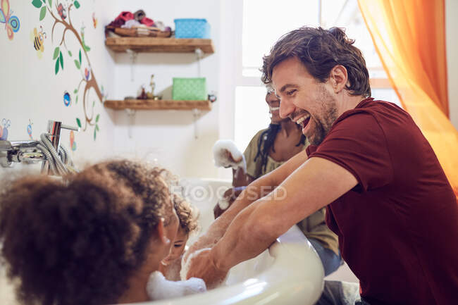 Щасливі батьки дарують дочкам бульбашкову ванну — стокове фото
