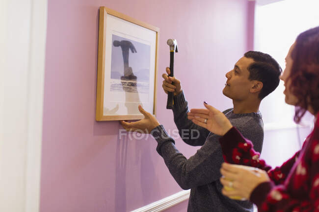 Casal redecorar, pendurado fotografia emoldurada na parede — Fotografia de Stock