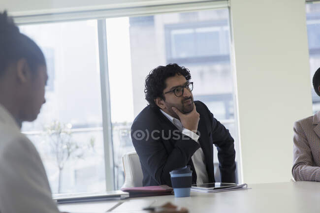 Pensativo hombre de negocios escuchando en la reunión de la sala de conferencias - foto de stock