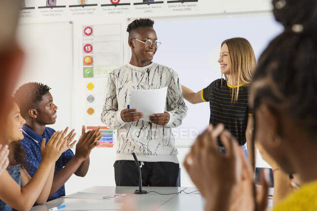Estudiantes de secundaria aplaudiendo a su compañero de clase en clase de debate - foto de stock