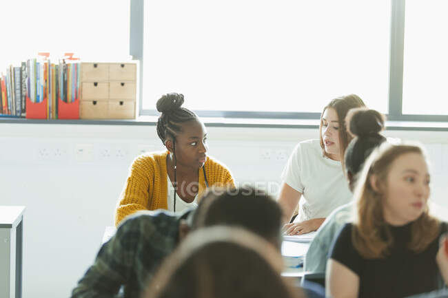 Estudantes do ensino médio conversando, fazendo lição de casa em sala de aula — Fotografia de Stock