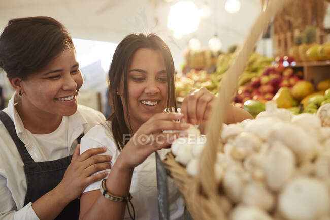Mujeres trabajadoras sonrientes organizando ajo en el mercado campesino - foto de stock
