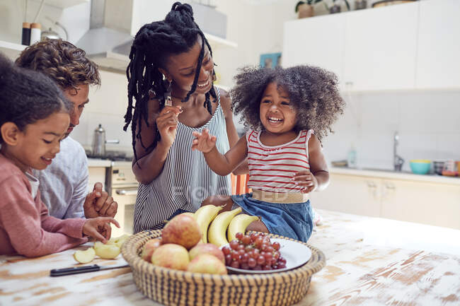 Молода сім'я їсть фрукти на кухні — стокове фото