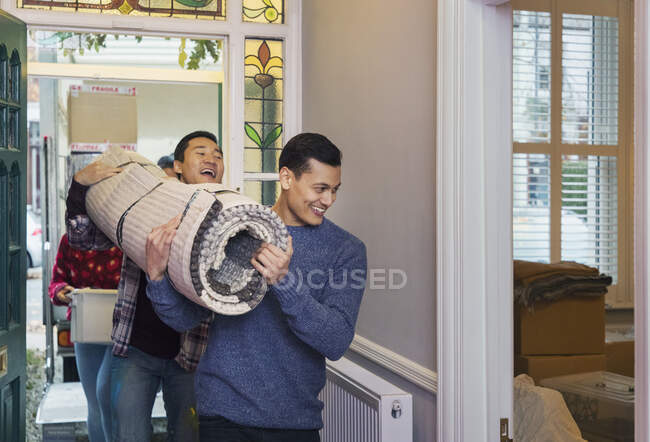 Мужчины передвигают дом, несут ковер в коридоре — стоковое фото