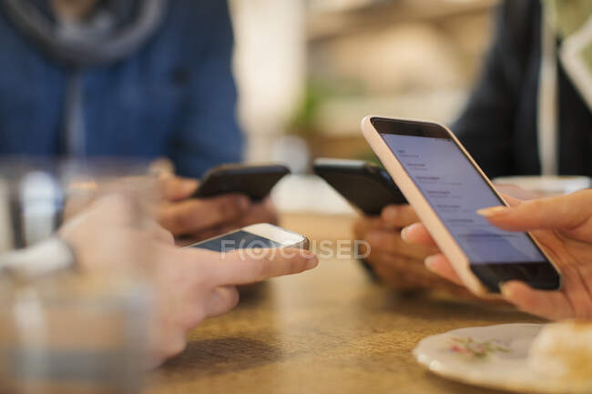 Adultos jóvenes usando teléfonos inteligentes en la mesa - foto de stock