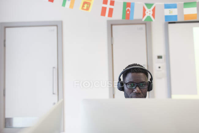 Mature male community college student with headphones at computer in classroom — Stock Photo
