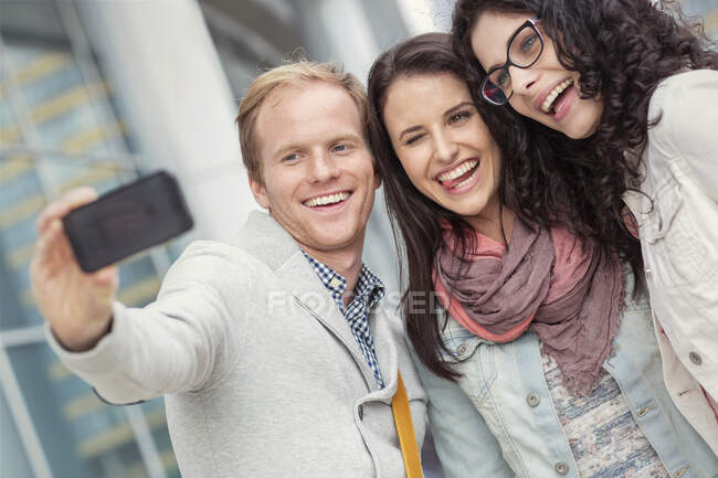Juguetones jóvenes amigos tomando selfie con cámara de teléfono - foto de stock