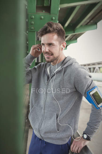 Мужчина бегун слушает музыку с наушниками и смартфоном — стоковое фото