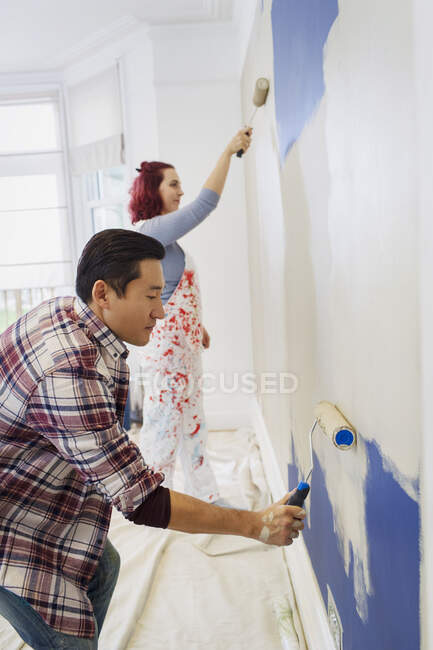 Parede de pintura de casal com rolos de pintura — Fotografia de Stock