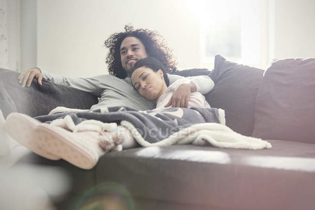 Ласковая пара расслабляется, смотрит телевизор на диване — стоковое фото
