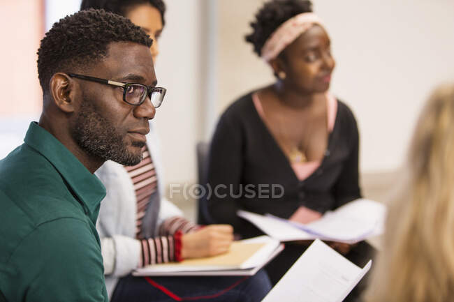 Empresário atento e focado com papelada ouvindo em reunião — Fotografia de Stock