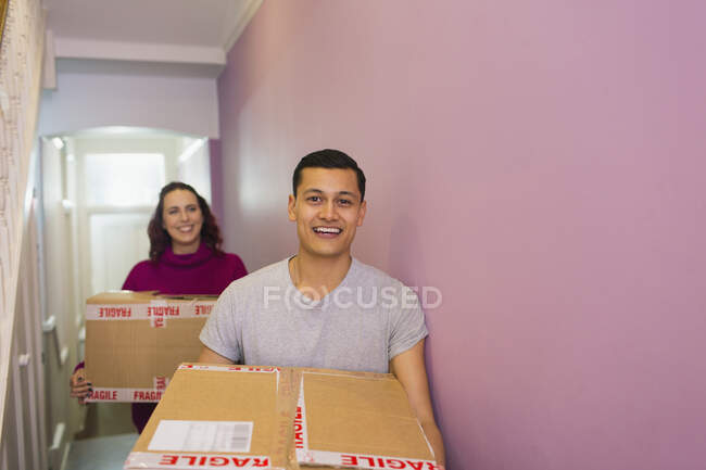 Portrait heureux couple déménagement maison, portant des boîtes en carton dans le couloir — Photo de stock