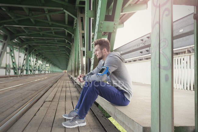 Corredor masculino sentado com smartphone na mão — Fotografia de Stock