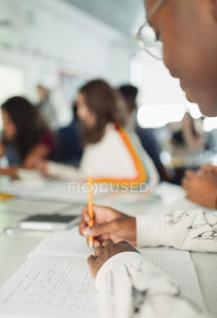 High school boy student taking notes, writing in notebook in classroom — Stock Photo