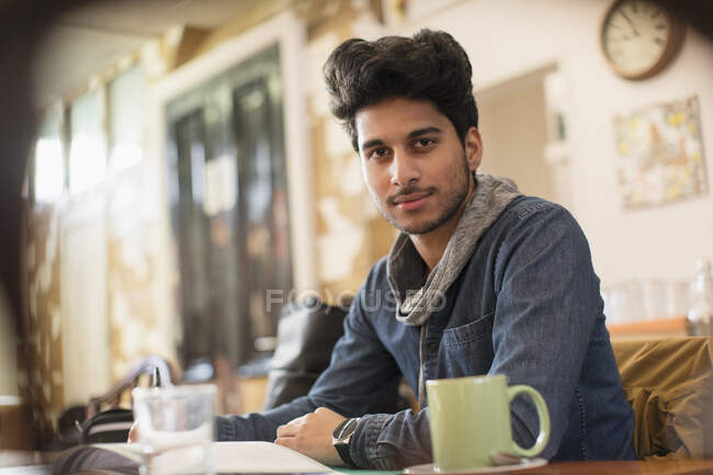 Ritratto fiducioso giovane studente di college maschile che studia in caffè — Foto stock
