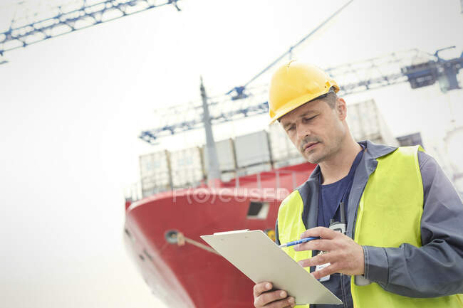 Dock worker with clipboard below container ship at shipyard — Stock Photo