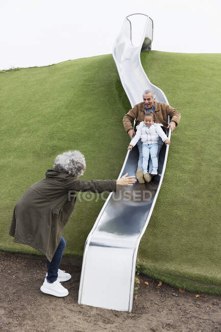 Бабусі і дідусі з онукою на ігровому майданчику слайд — стокове фото