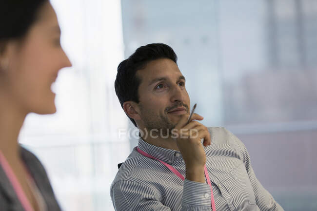 Улыбающийся бизнесмен слушает на встрече — стоковое фото