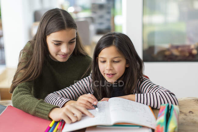 Девушка помогает младшей сестре с домашним заданием — стоковое фото