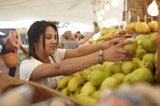 Жінка працює, організовує груші на ринку фермерів — стокове фото