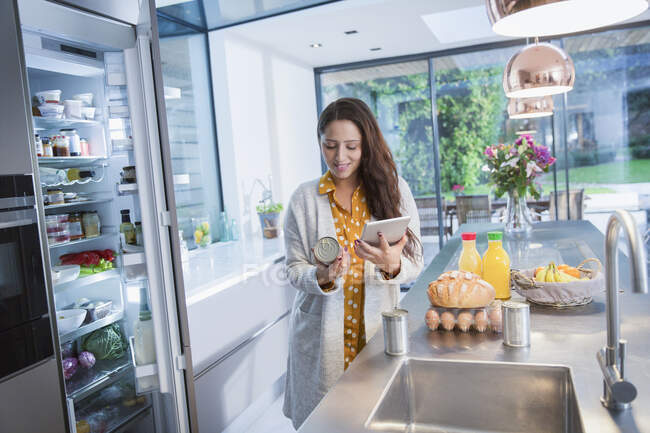 Frau mit digitalem Tablet überprüft Lebensmitteletiketten in Küche — Stockfoto