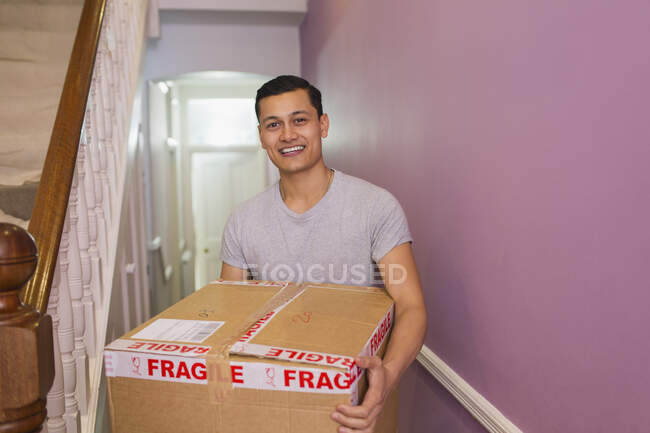 Portrait happy man carrying moving box in corridor — Stock Photo