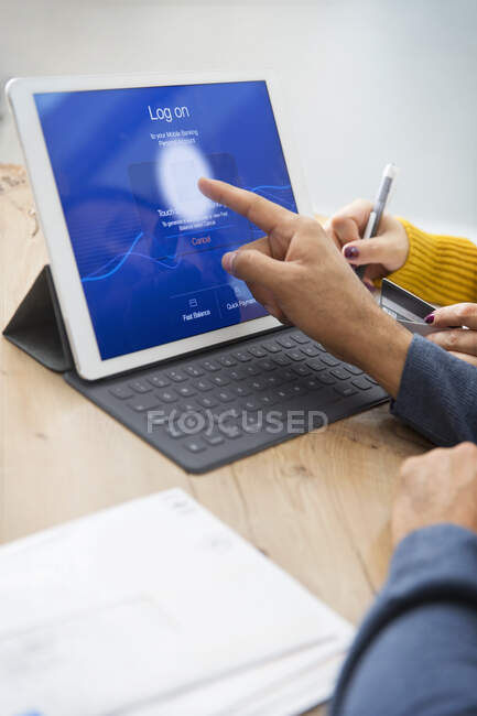 Couple paying bills, logging on to digital tablet with fingerprint — Stock Photo