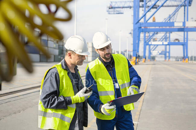 Dock workers with walkie-talkie and clipboard meeting at shipyard — Stock Photo