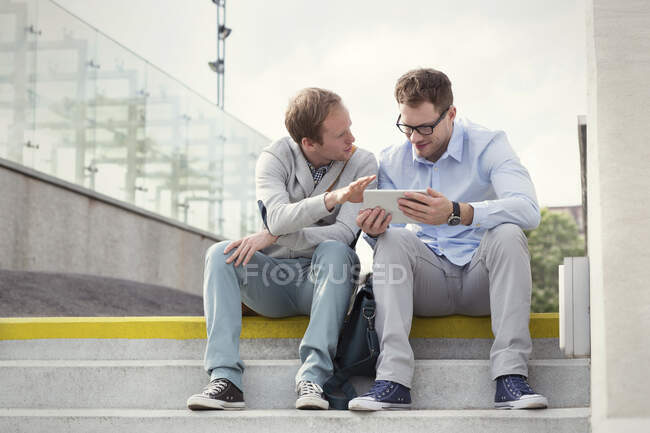 Les hommes d'affaires parlent, en utilisant une tablette numérique sur les étapes — Photo de stock